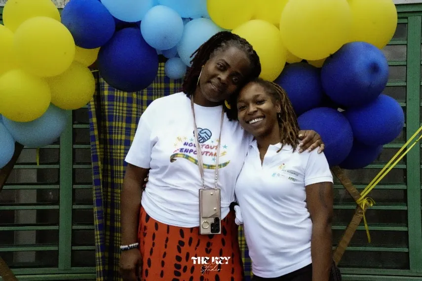 Deux femmes souriantes devant une arche de ballons bleus et jaunes, lors de la Journée mondiale de la trisomie 21 à Sainte-Rose
