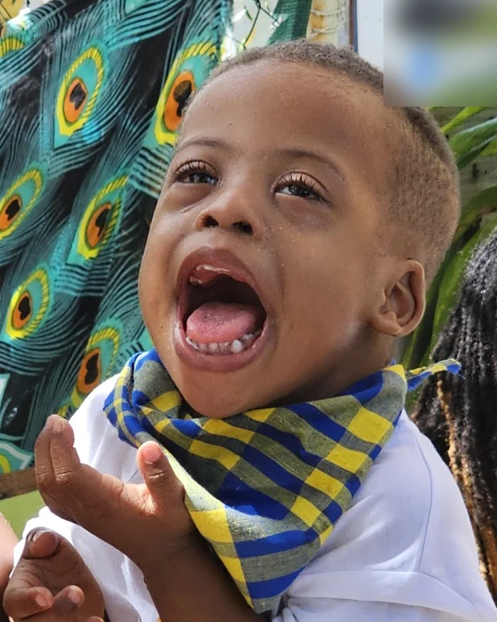 Ely-Hangel, un petit garçon souriant, un foulard madras jaune et bleu noué autour du cou