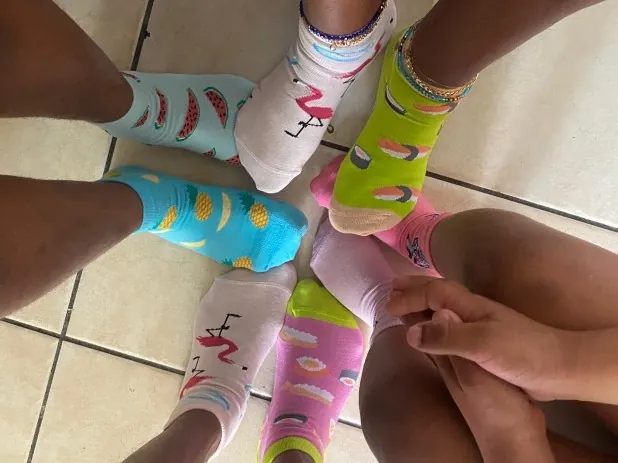Des pieds en cercle, chacun dans une chaussette différente : pastèques, ananas, flamants roses, sushis